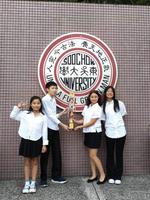 學生在東吳大學標誌前持獎盃合影